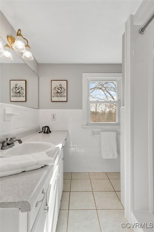 bathroom with tile patterned flooring, wainscoting, vanity, and tile walls