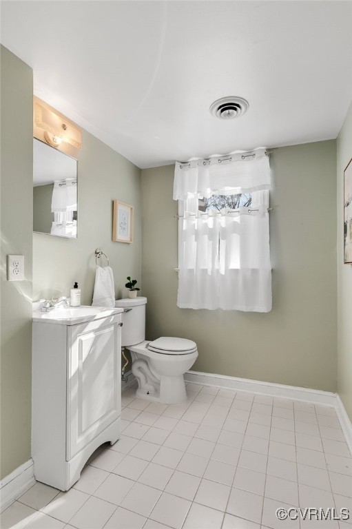 half bath with visible vents, baseboards, toilet, and vanity