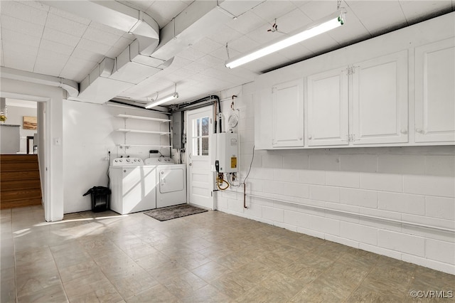 basement featuring stairs, concrete block wall, water heater, and washer and clothes dryer