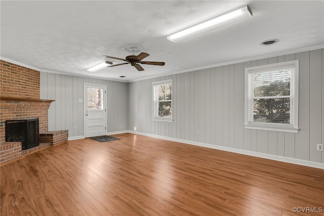 unfurnished living room featuring visible vents, a fireplace, crown molding, and wood finished floors