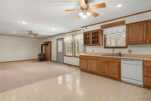 kitchen featuring dishwasher, crown molding, a wood stove, and a sink