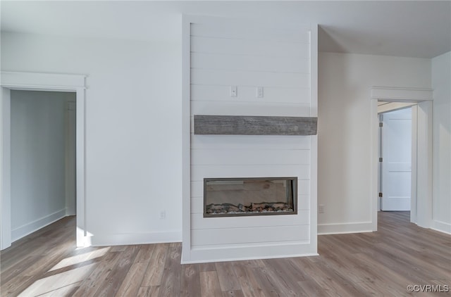 unfurnished living room with wood finished floors, a fireplace, and baseboards