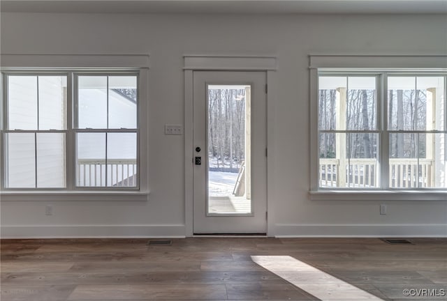 doorway with visible vents, baseboards, and wood finished floors