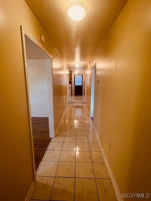 hall with light tile patterned floors and baseboards