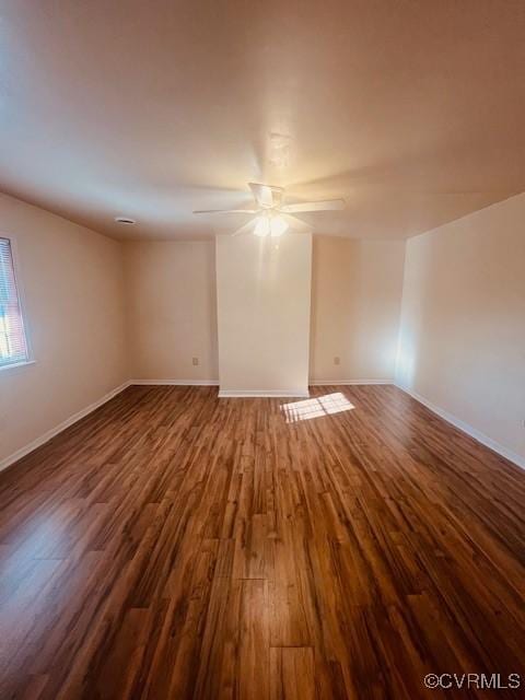 spare room with baseboards, dark wood-type flooring, and ceiling fan