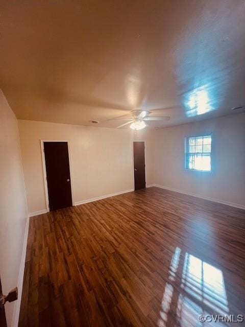 unfurnished room featuring dark wood-type flooring, baseboards, and ceiling fan