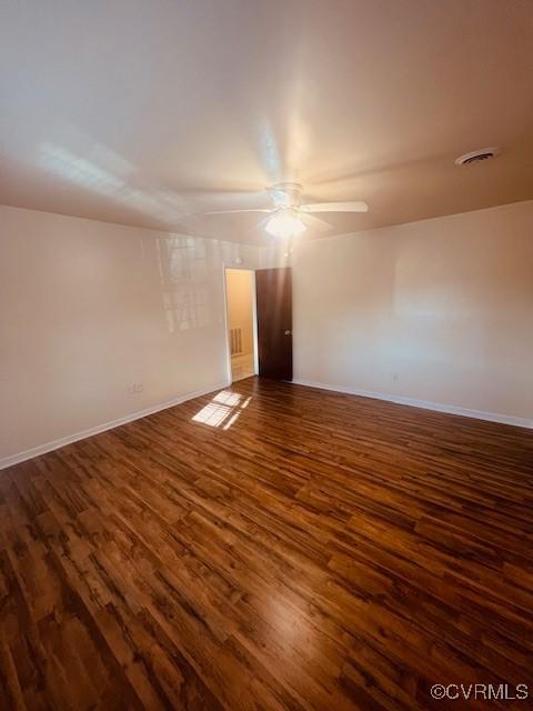 unfurnished room with dark wood finished floors, visible vents, ceiling fan, and baseboards