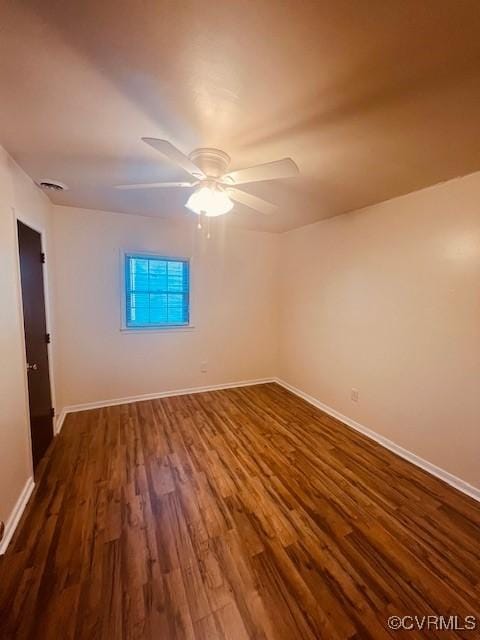 spare room featuring a ceiling fan, dark wood-style floors, and baseboards