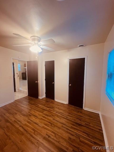 empty room featuring a ceiling fan, baseboards, and wood finished floors