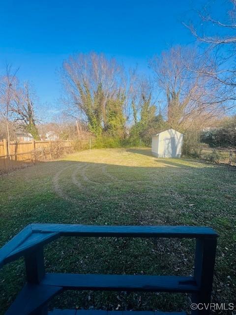 view of yard with fence, an outbuilding, and a shed