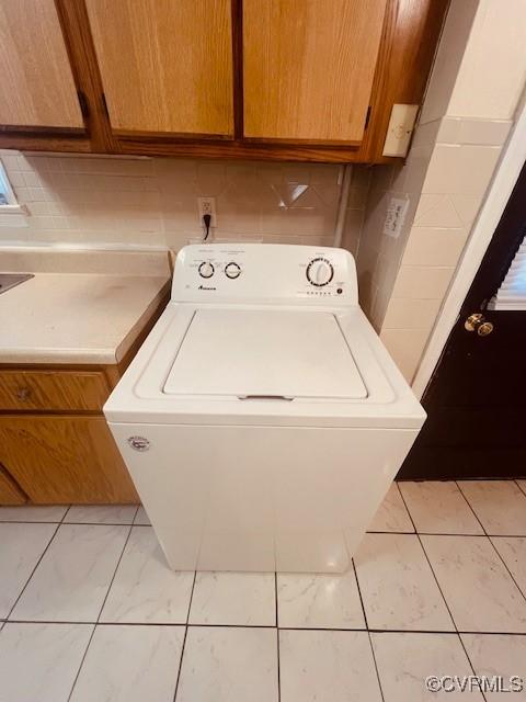 clothes washing area with washer / clothes dryer and cabinet space