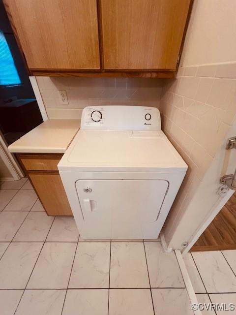 clothes washing area with cabinet space, washer / dryer, tile walls, and marble finish floor