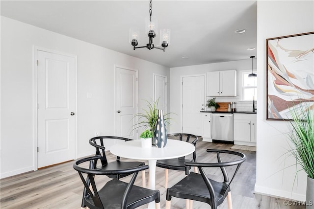 dining space with baseboards, light wood-style floors, and a chandelier