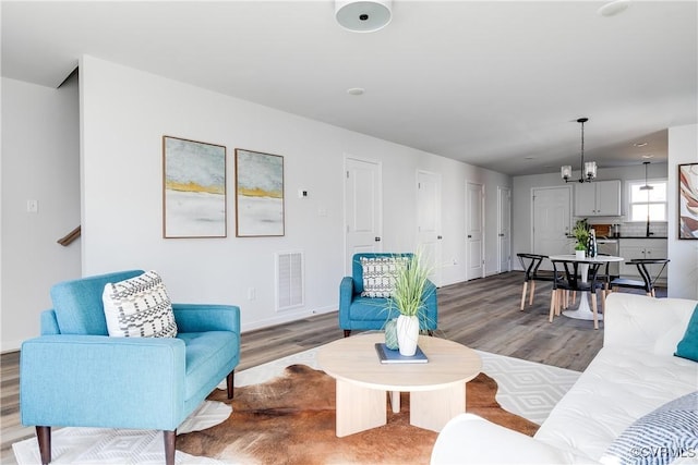 living room with visible vents, wood finished floors, and a chandelier