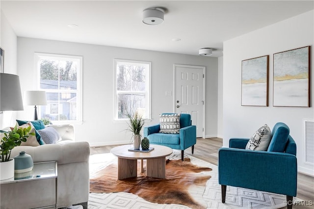 living area featuring visible vents, wood finished floors, and baseboards