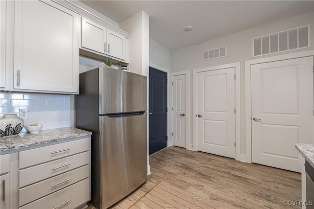 10530 Stony Bluff Dr Unit 205, Ashland, VA 23005 - kitchen with decorative backsplash, light wood-style floors, visible vents, and freestanding refrigerator