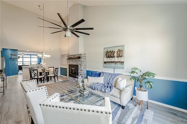 living area featuring wood finished floors, a fireplace, baseboards, and high vaulted ceiling