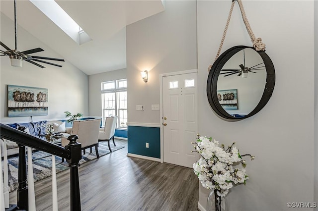 entryway featuring baseboards, high vaulted ceiling, dark wood finished floors, a skylight, and ceiling fan