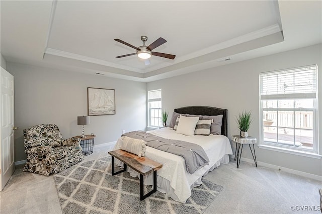 bedroom with a tray ceiling, multiple windows, light colored carpet, and baseboards