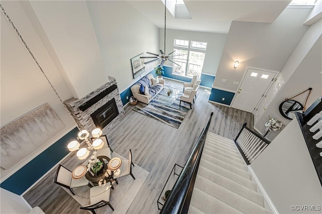 living room featuring a ceiling fan, a glass covered fireplace, wood finished floors, baseboards, and stairs