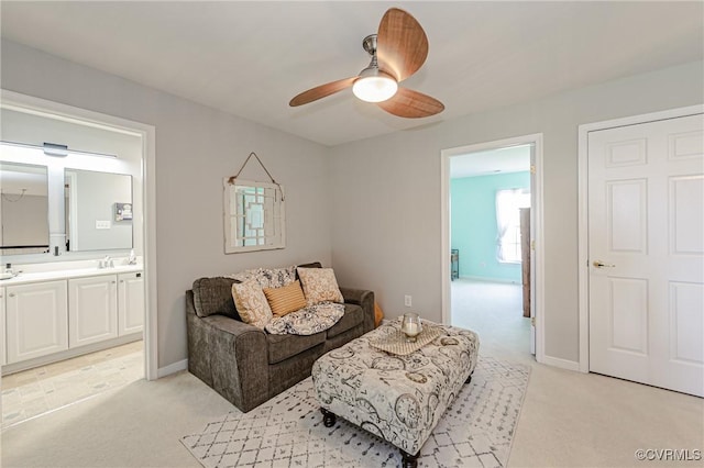 living area featuring light colored carpet, baseboards, and a ceiling fan