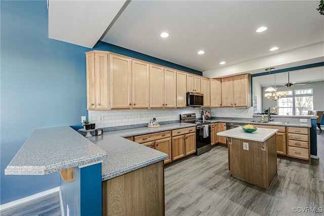 kitchen featuring a peninsula, a sink, stainless steel appliances, light countertops, and tasteful backsplash