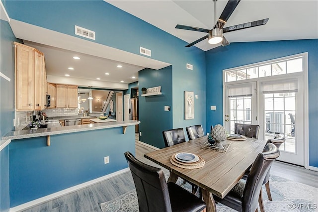 dining space featuring visible vents, light wood-style flooring, and lofted ceiling