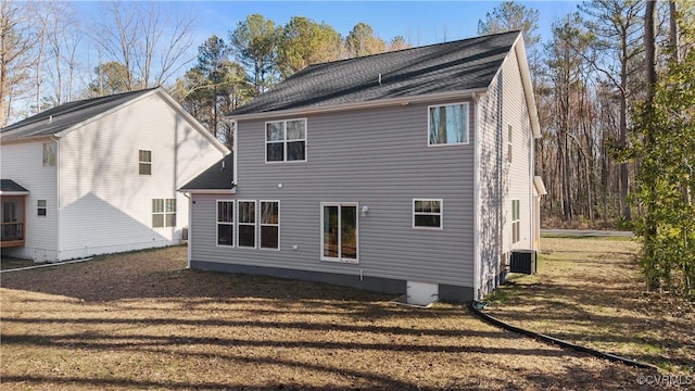 back of property with central AC unit and a lawn