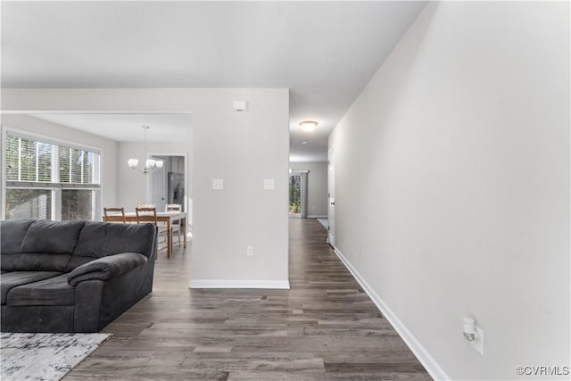 living room featuring an inviting chandelier, wood finished floors, and baseboards