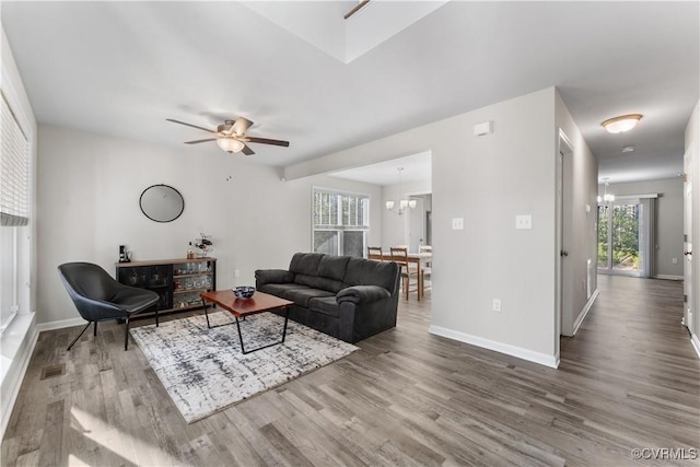 living room featuring baseboards, wood finished floors, and ceiling fan with notable chandelier