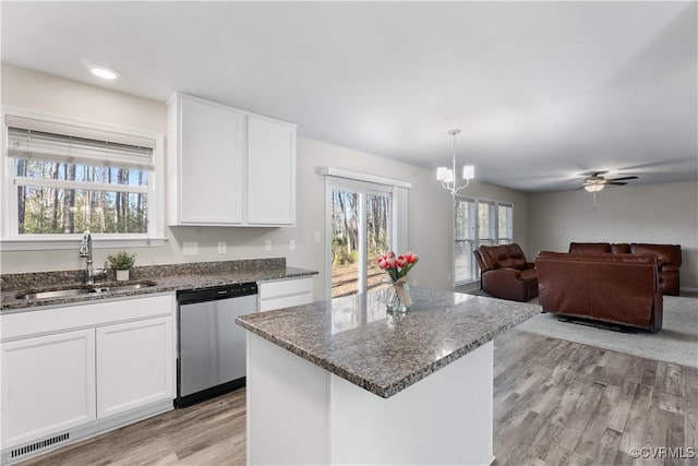 kitchen with visible vents, dishwasher, dark stone countertops, white cabinets, and a sink