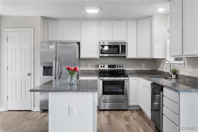 kitchen with a sink, dark stone countertops, white cabinets, and stainless steel appliances