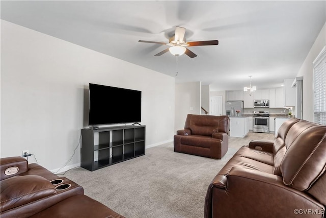 living room featuring baseboards, light carpet, and ceiling fan with notable chandelier