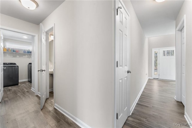 corridor featuring washing machine and dryer, baseboards, and wood finished floors