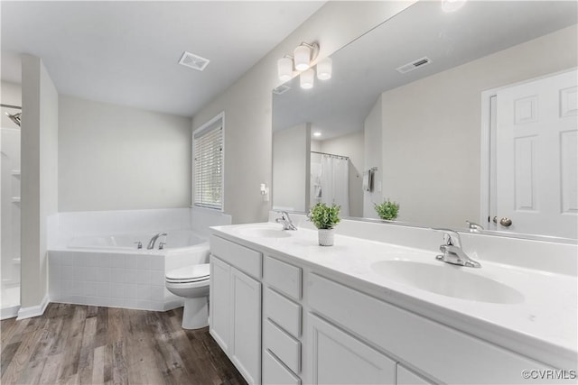 bathroom with visible vents, wood finished floors, a garden tub, and a sink