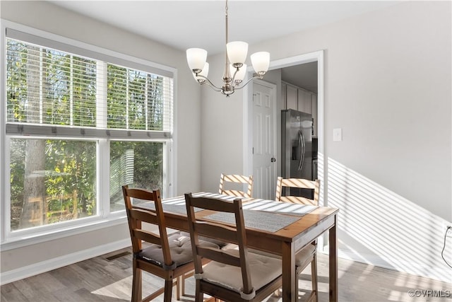 dining space with a chandelier, plenty of natural light, baseboards, and wood finished floors