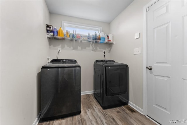 laundry room with wood finished floors, baseboards, visible vents, laundry area, and separate washer and dryer