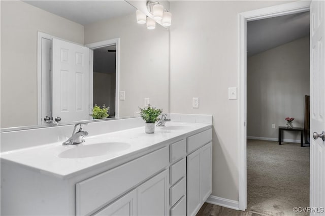 bathroom with double vanity, baseboards, and a sink