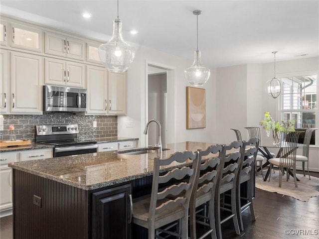 kitchen with a sink, tasteful backsplash, appliances with stainless steel finishes, and dark wood finished floors