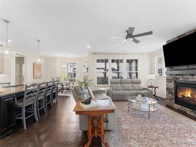 living area with dark wood-style floors, a stone fireplace, recessed lighting, and ceiling fan