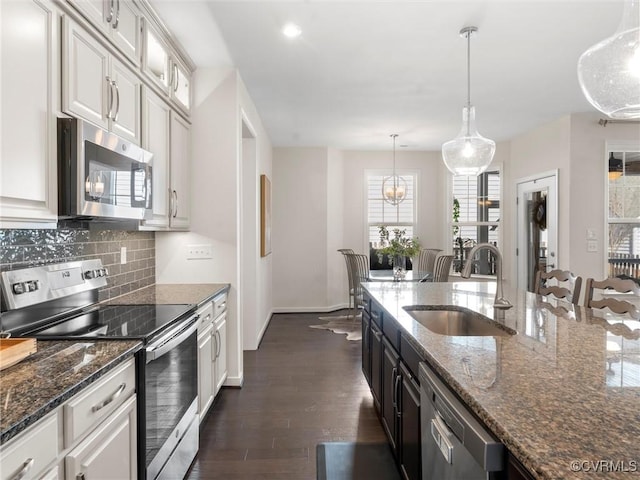 kitchen with dark wood finished floors, a sink, stainless steel appliances, glass insert cabinets, and tasteful backsplash