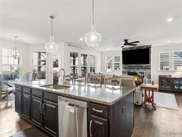 kitchen with a kitchen island with sink, dishwasher, dark wood-type flooring, and a sink