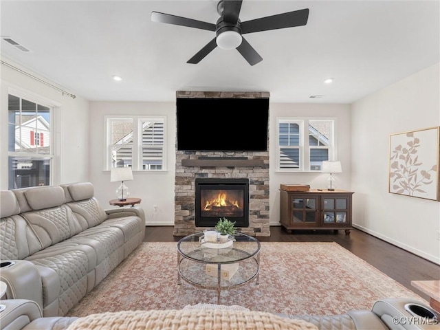 living room featuring a fireplace, wood finished floors, visible vents, and baseboards