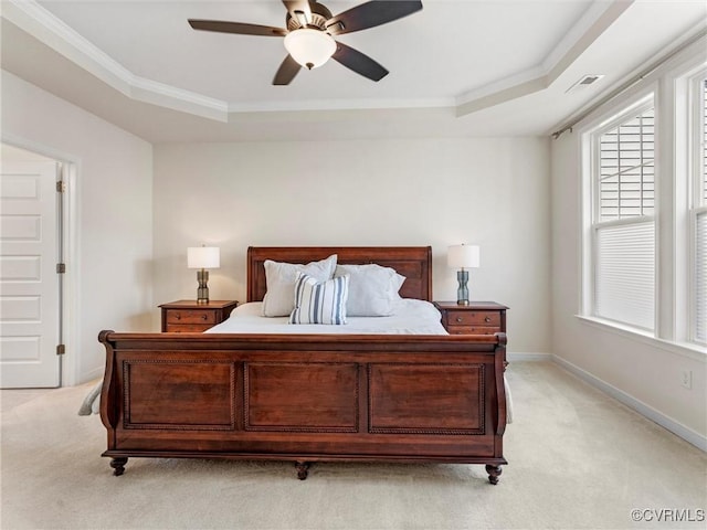 bedroom featuring light colored carpet, baseboards, crown molding, and a tray ceiling