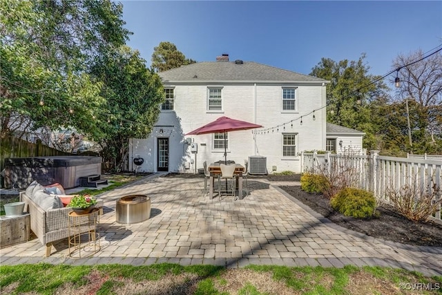 rear view of property with a patio area, central AC unit, a hot tub, and fence