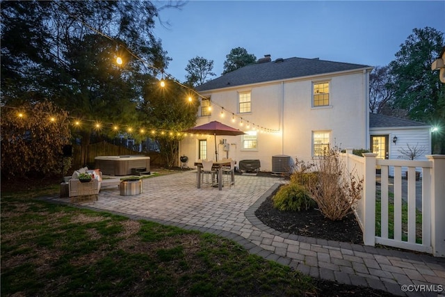 back of house featuring a patio area, fence, roof with shingles, and a hot tub