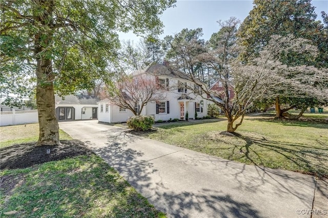 view of front of home featuring a front lawn, concrete driveway, and fence