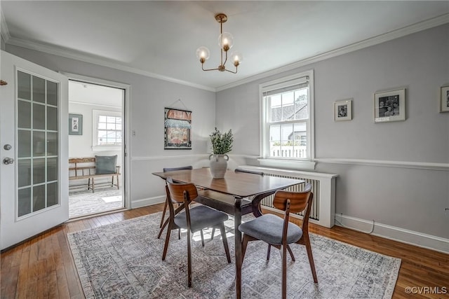 dining area featuring a chandelier, wood-type flooring, radiator, and ornamental molding