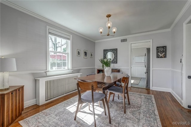 dining space with visible vents, a chandelier, hardwood / wood-style floors, and ornamental molding