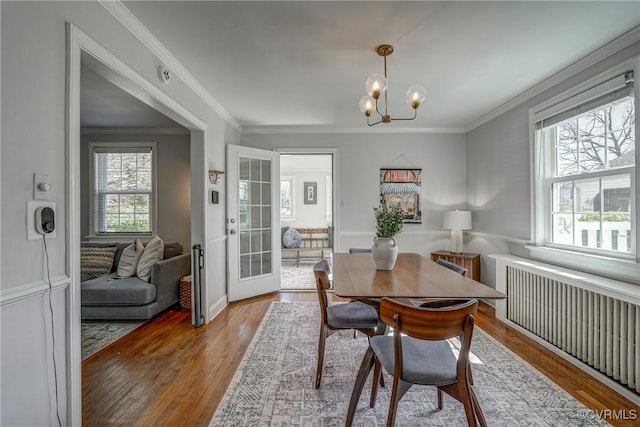 dining space featuring an inviting chandelier, wood finished floors, radiator heating unit, and crown molding